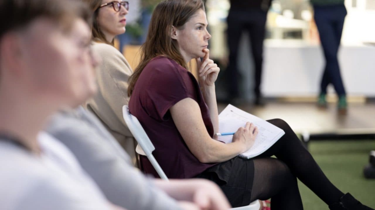 People listening and taking notes at a workshop